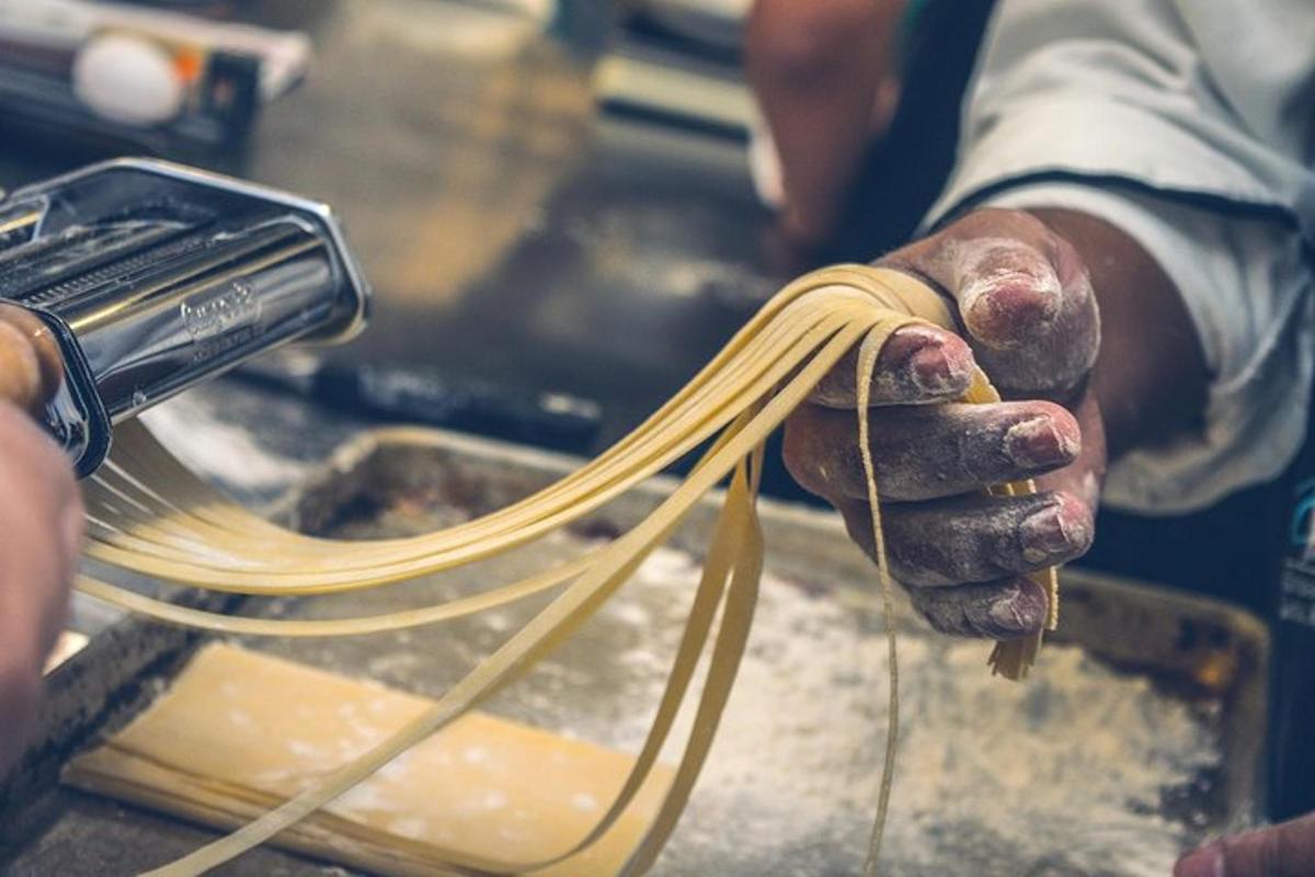 seseorang yang memegang sekeping spageti di tangan
