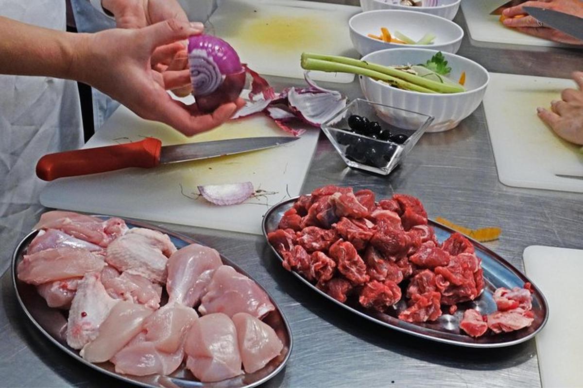 ένα τραπέζι με κρέας και λαχανικά και ένα άτομο που μαγειρεύει