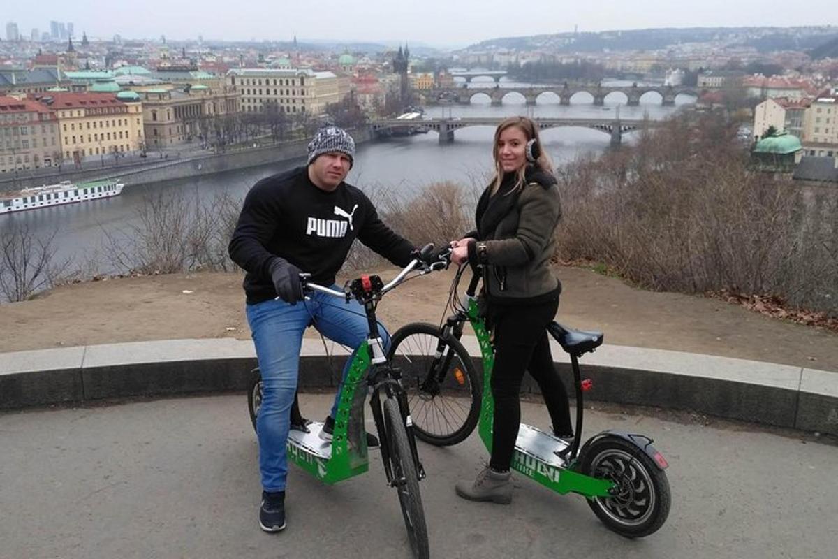 Un hombre y una mujer de pie con bicicletas y un scooter.