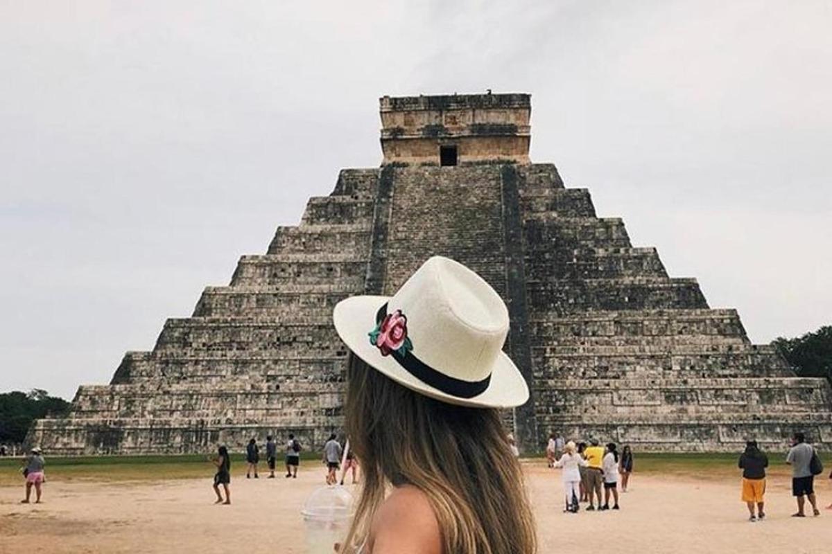una donna con un cappello in piedi davanti a una piramide