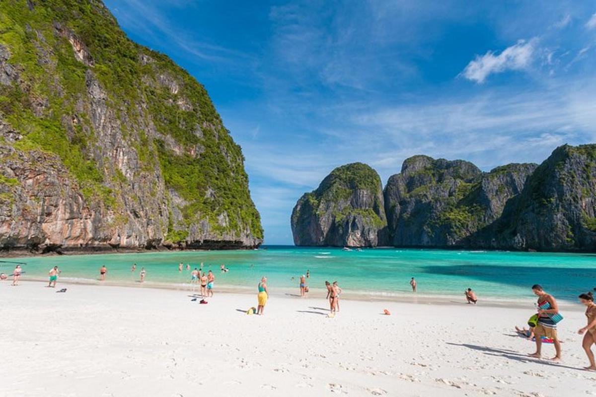 sekumpulan manusia di pantai dengan tebing batu kapur