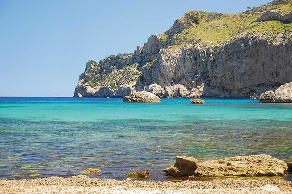 una platja amb roques i aigua blava i una muntanya