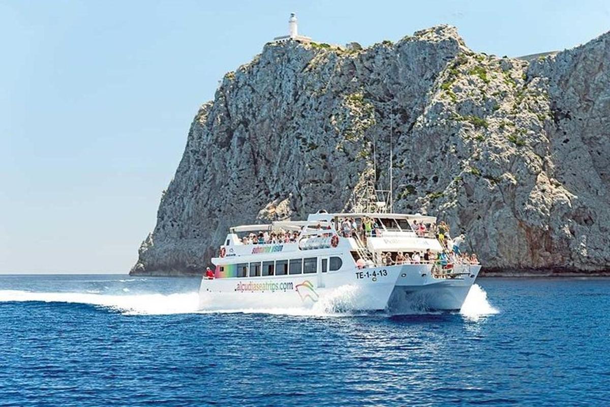 um barco branco na água perto de uma ilha rochosa