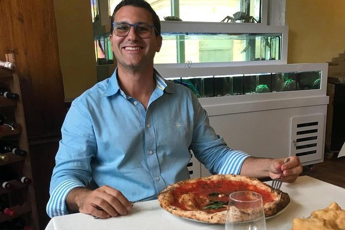 maður situr við borð með pizzu