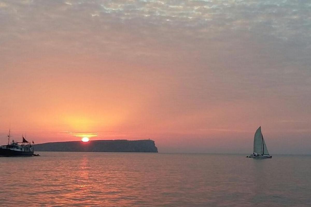 a sail boat in the ocean at sunset