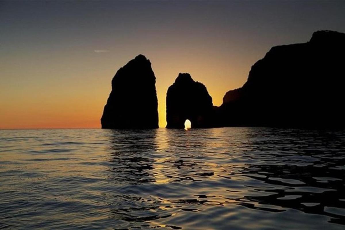 un apus de soare peste ocean cu pietre în apă