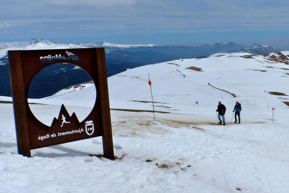 duas pessoas esquiando em uma montanha coberta de neve com uma placa