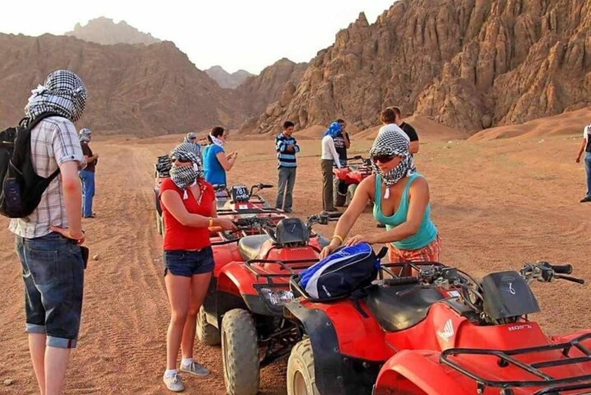Un grupo de personas de pie alrededor de vehículos todo terreno en el desierto.