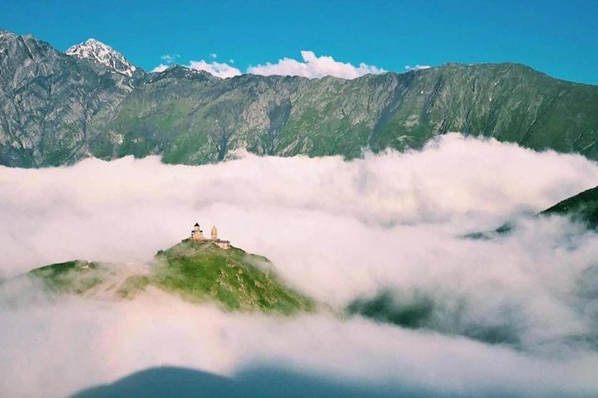 una montagna tra le nuvole con un faro in cima