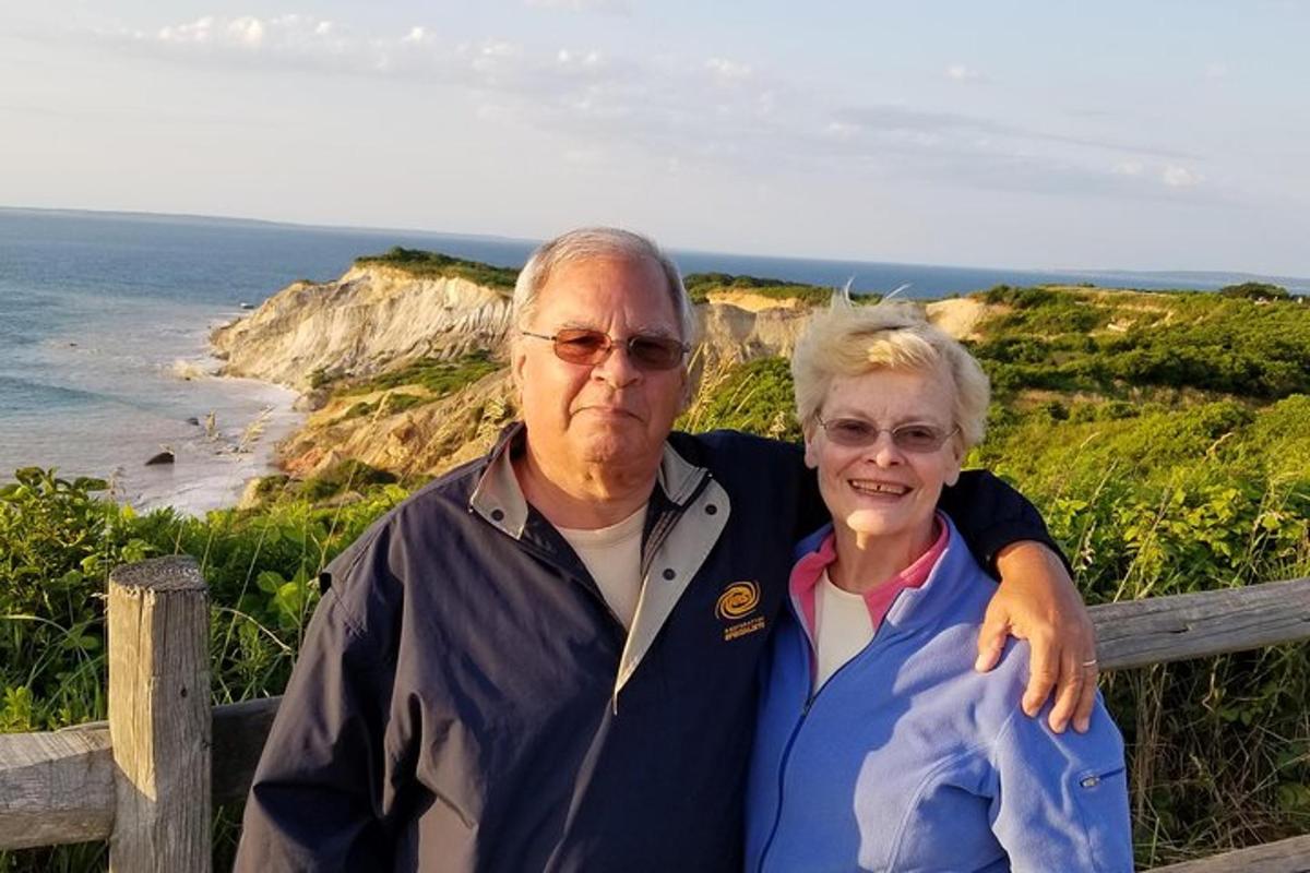 an older man and woman standing next to the ocean