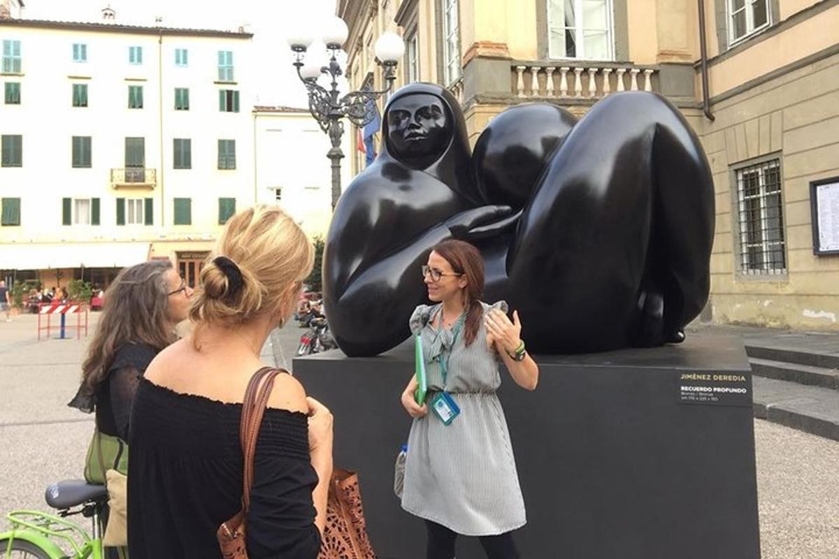 two women standing in front of a sculpture of people