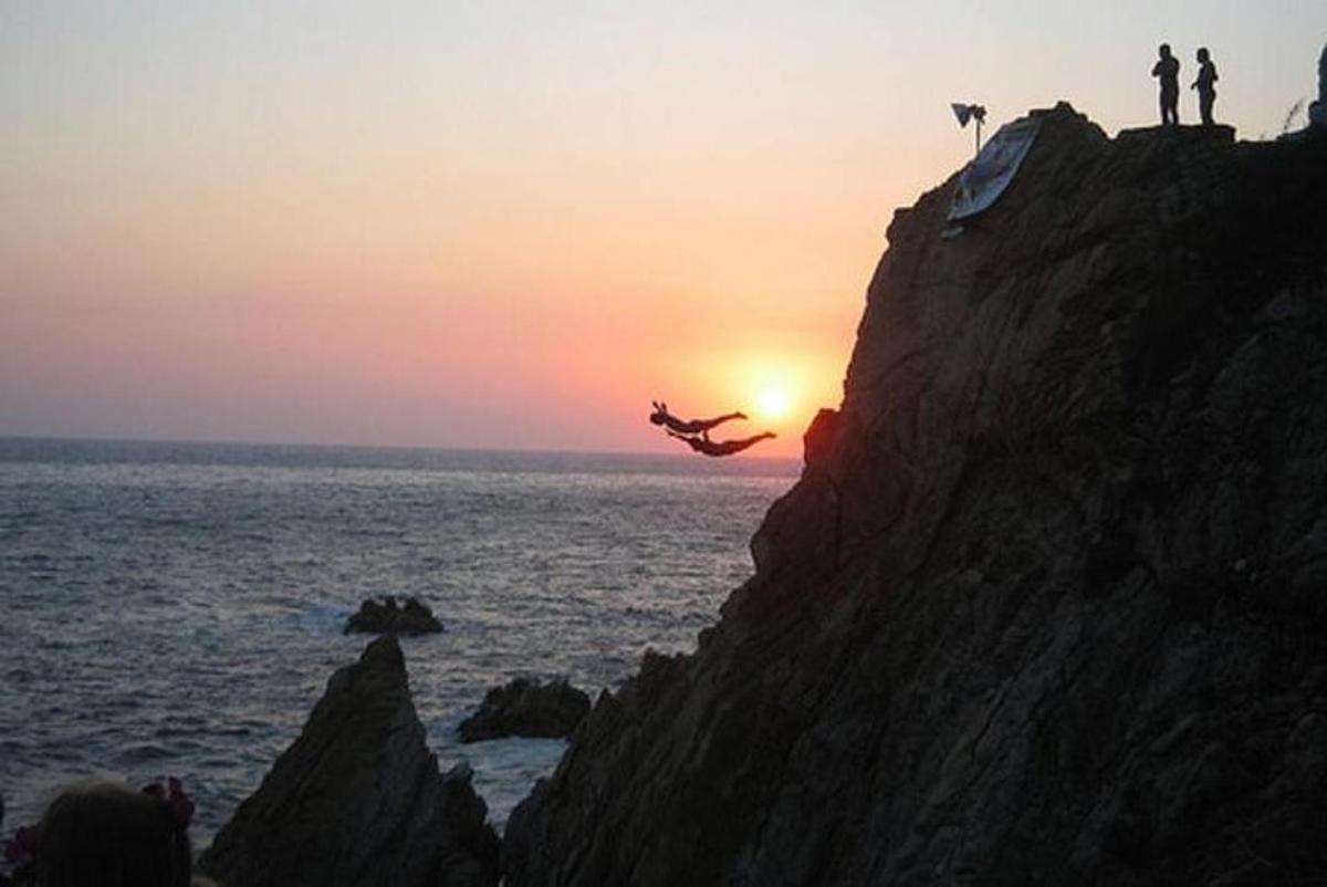a person doing a trick on a cliff at sunset