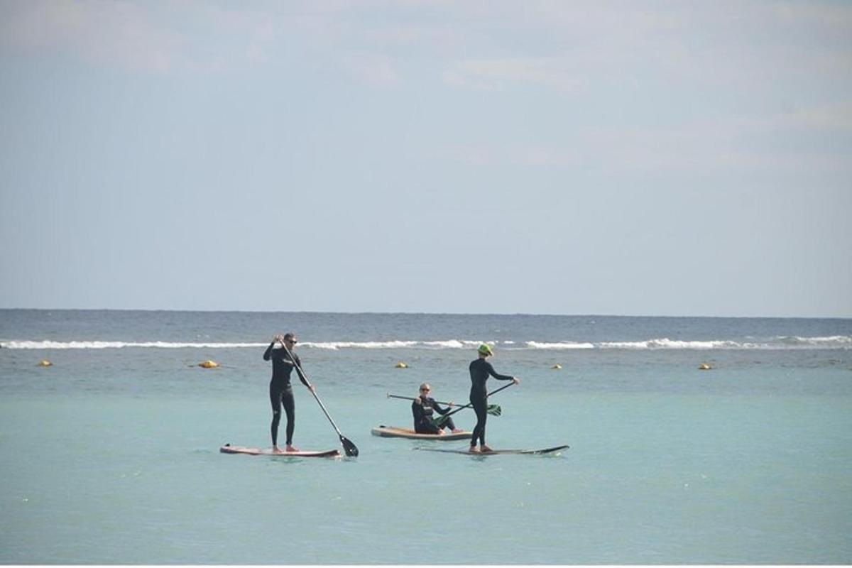 trois personnes se tiennent debout sur des planches de surf dans l'océan