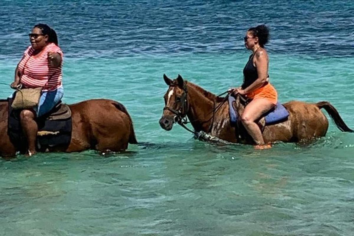 dua wanita menunggang kuda di dalam air di pantai