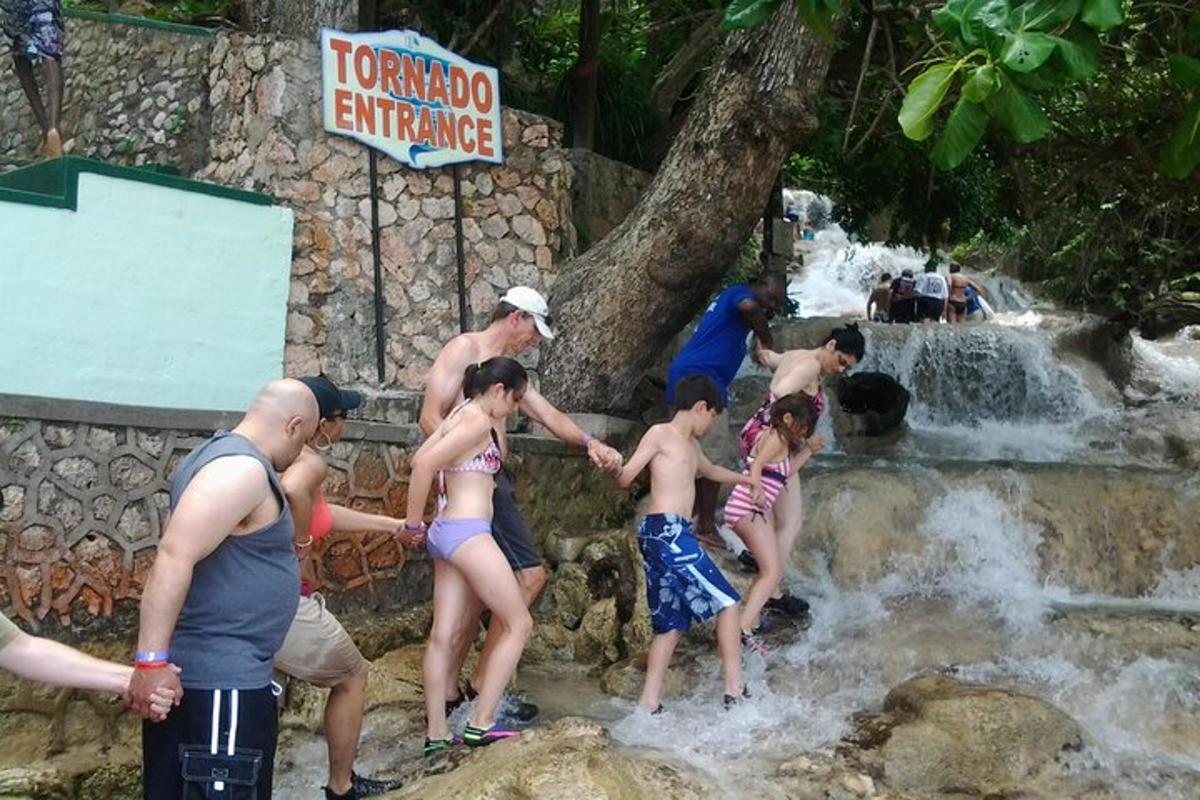 a group of people in the water at a waterfall