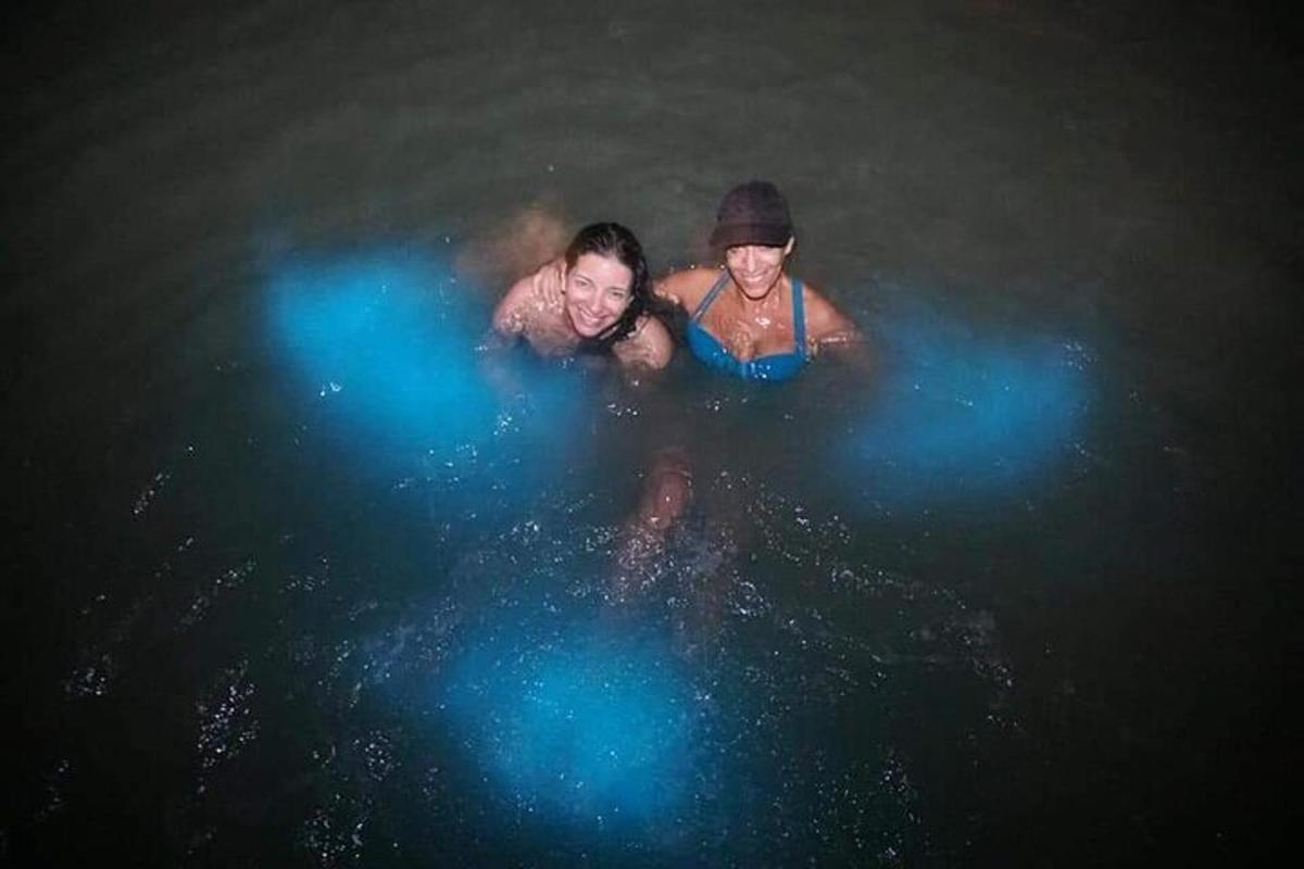 tre persone che nuotano nell'acqua di notte