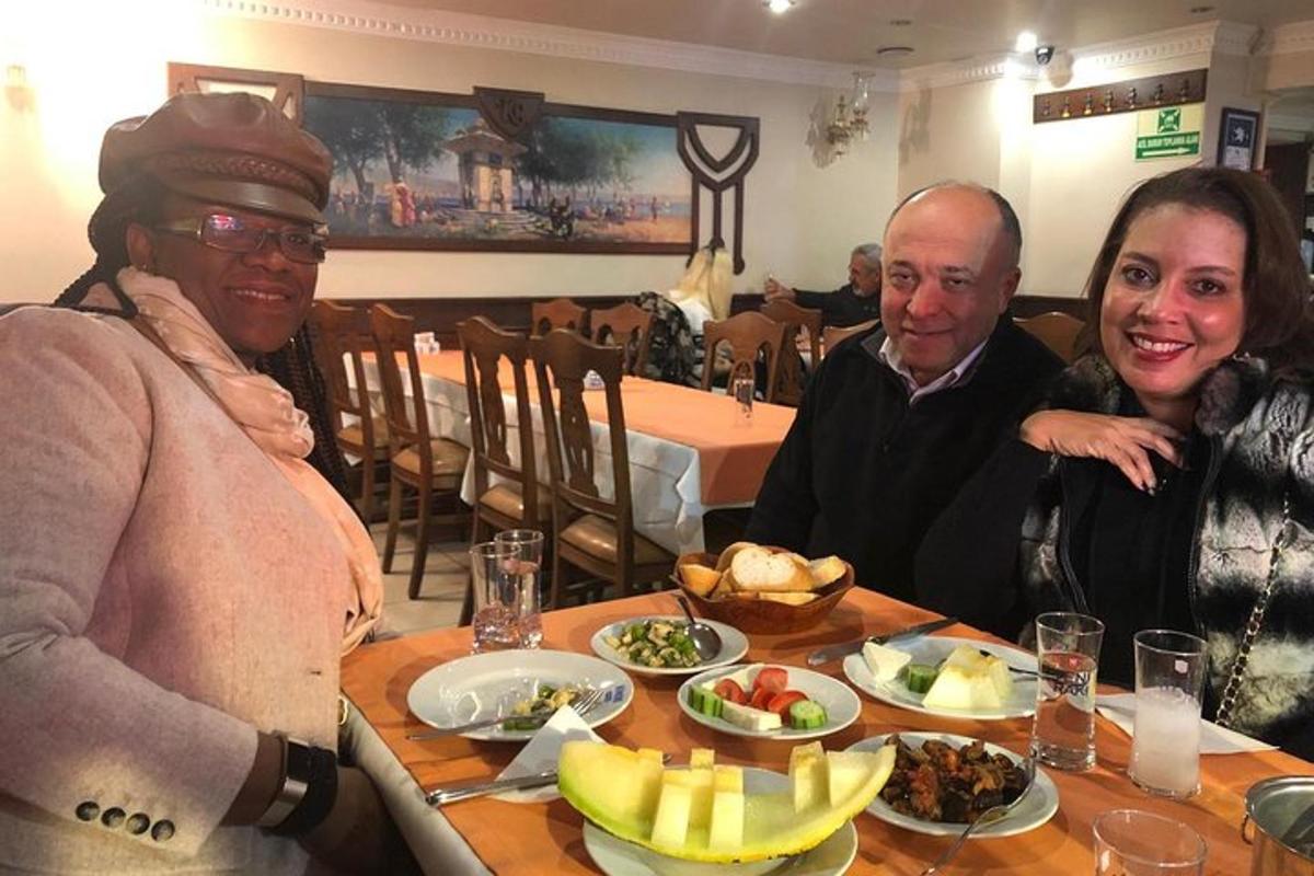 a group of three people sitting at a table with food
