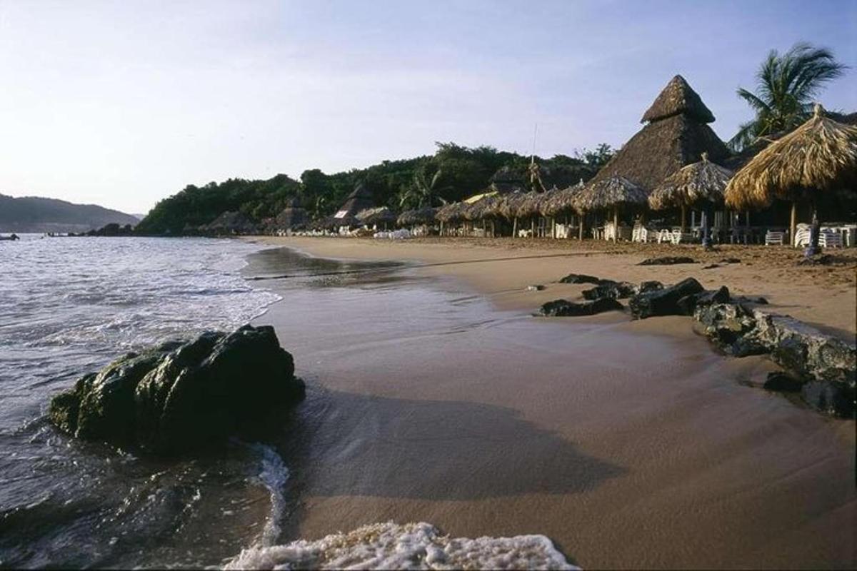 a beach with some straw umbrellas and the ocean