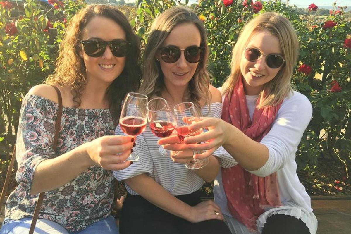 three women holding up glasses of red wine