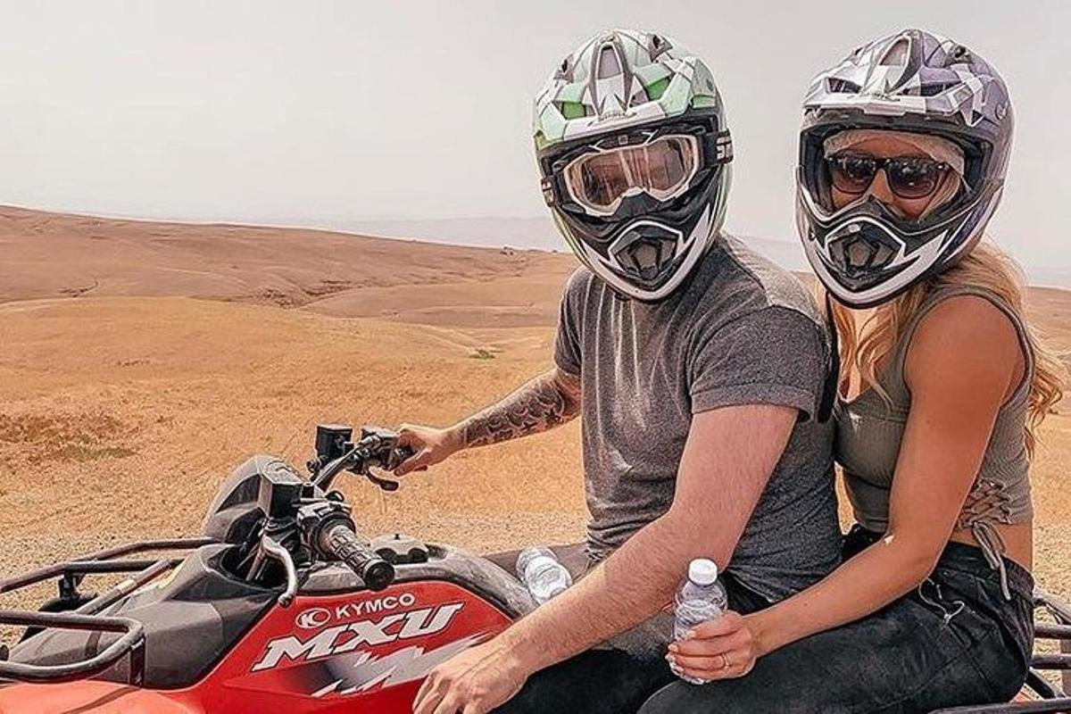 a man and woman sitting on a motorcycle in the desert