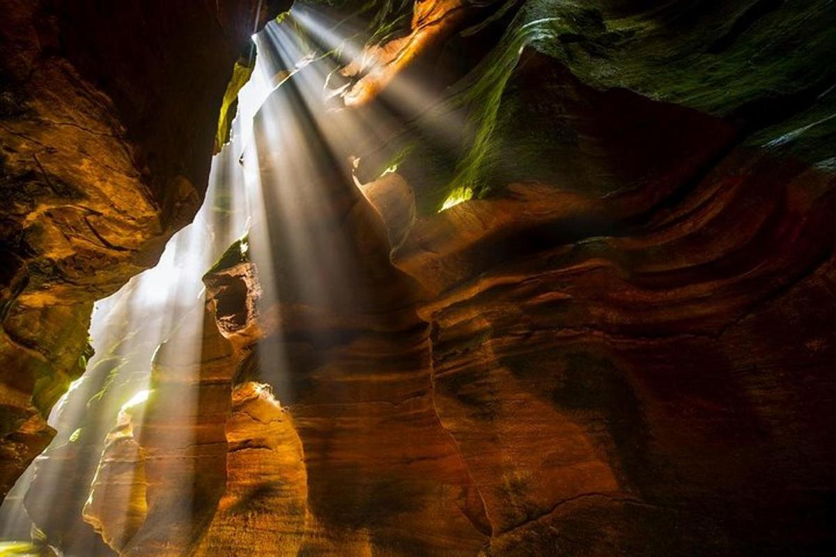 a shaft of light in a cave with a waterfall