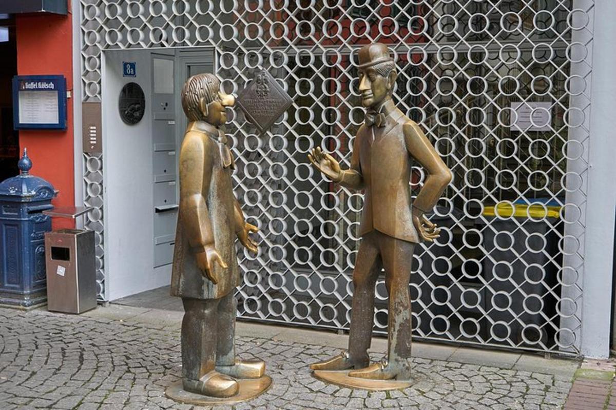 két bronz férfiszobor áll egy épület előtt