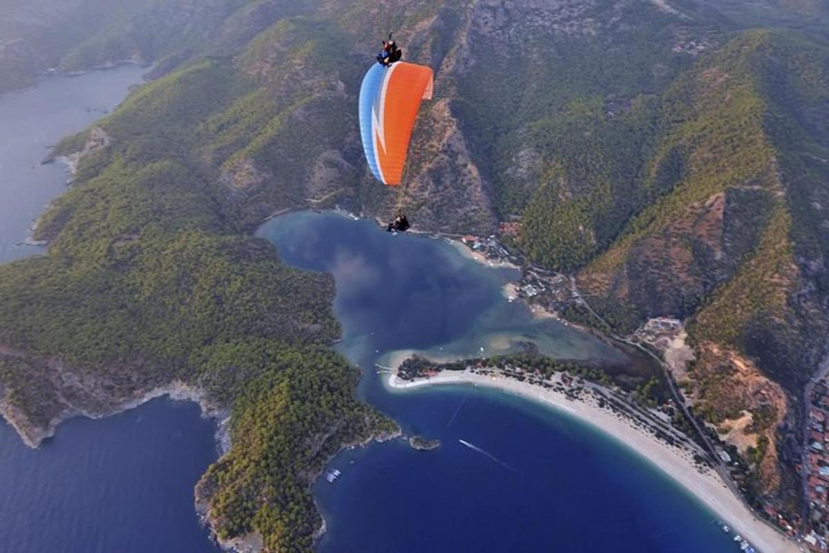 Ένα πορτοκαλί και άσπρο αλεξίπτωτο που πετάει πάνω από μια λίμνη