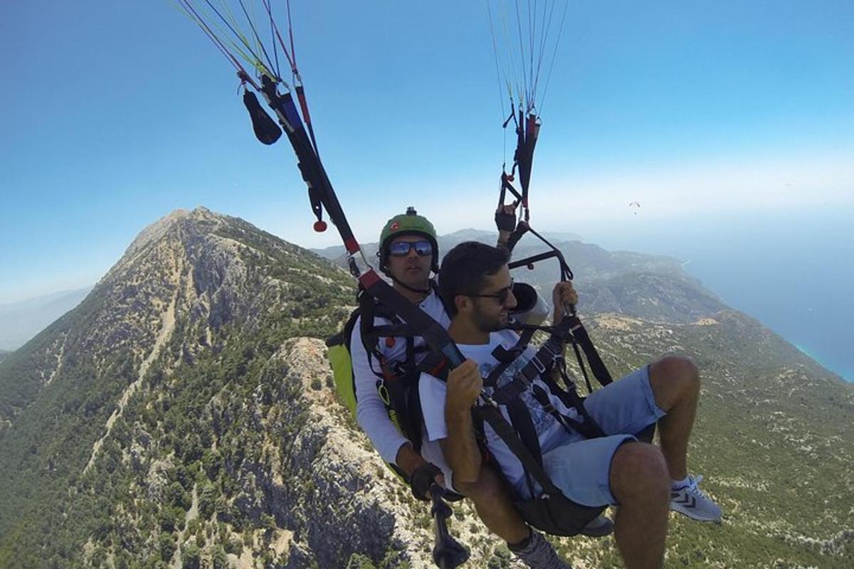 Δύο άνθρωποι κάθονται στην κορυφή ενός βουνού με αλεξίπτωτο