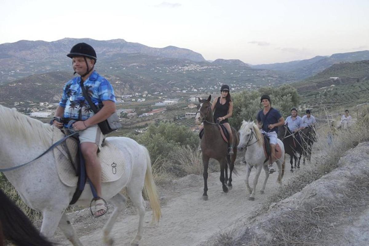 a group of people riding horses down a hill
