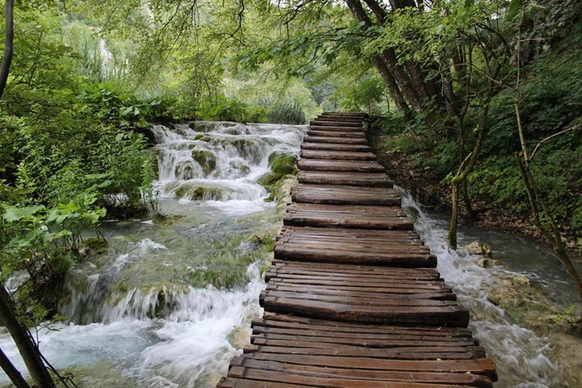 eine Holzbrücke über einen Fluss mit Wasserfällen