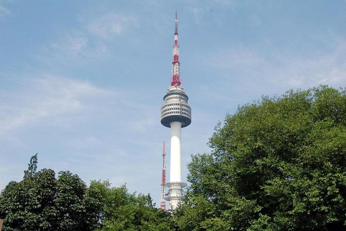 a tv tower in the sky with trees in the foreground