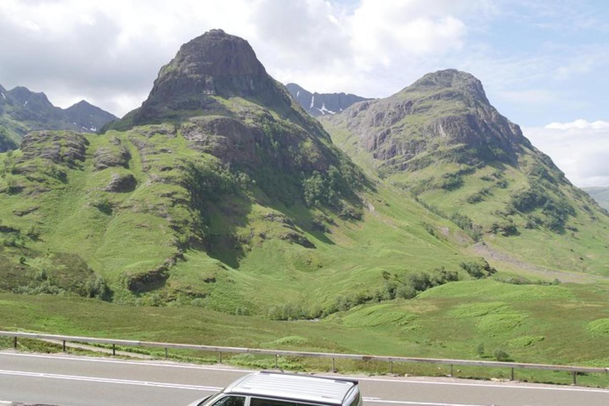 um carro dirigindo em uma estrada em frente a uma montanha