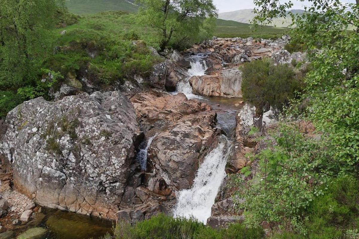 uma cachoeira em uma montanha rochosa com árvores e água