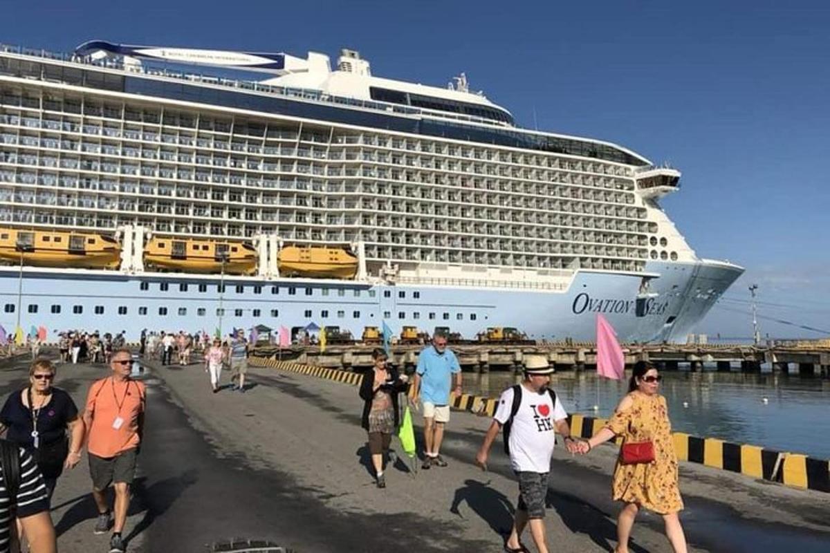 isang grupo ng mga taong naglalakad sa dalampasigan sa harap ng isang cruise ship
