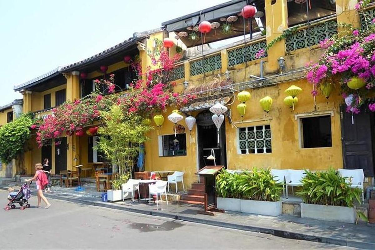 Una mujer caminando frente a un edificio amarillo con flores.
