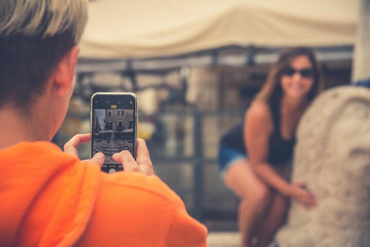 moški, ki fotografira žensko z mobilnim telefonom