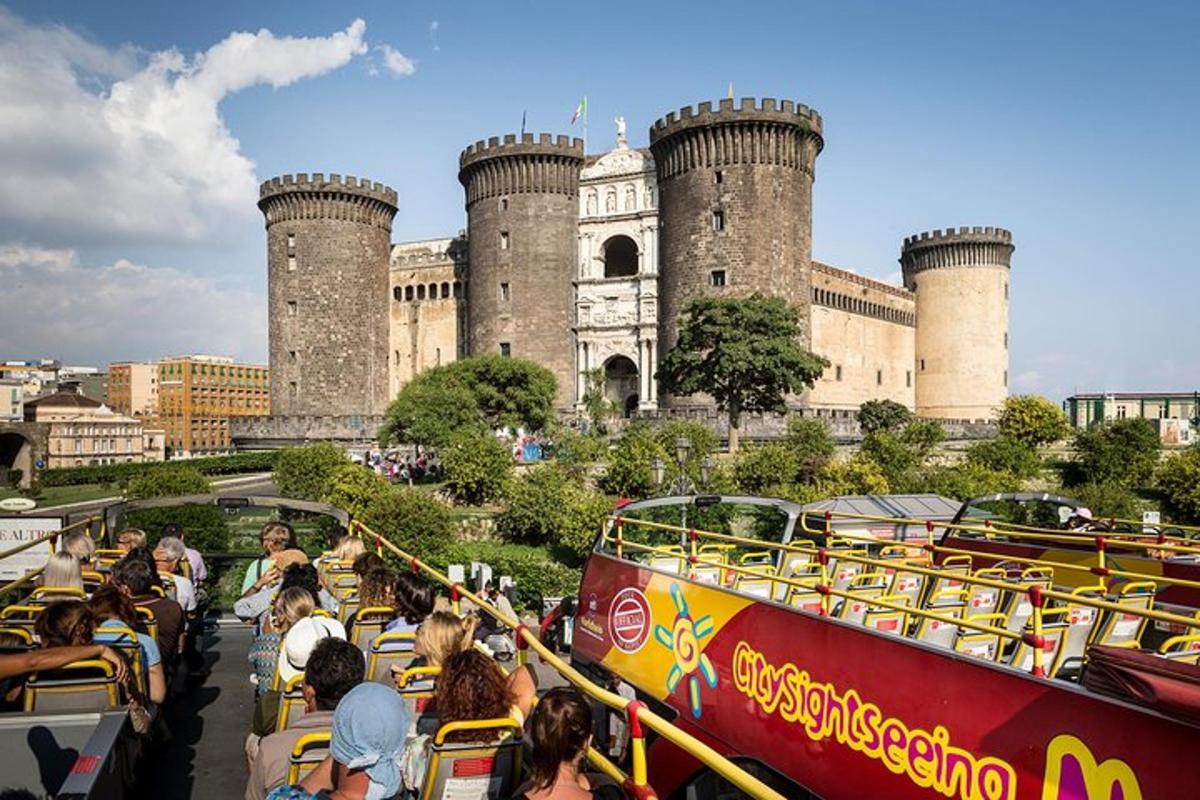 gent que viatja en un autobús de dos pisos davant d'un castell