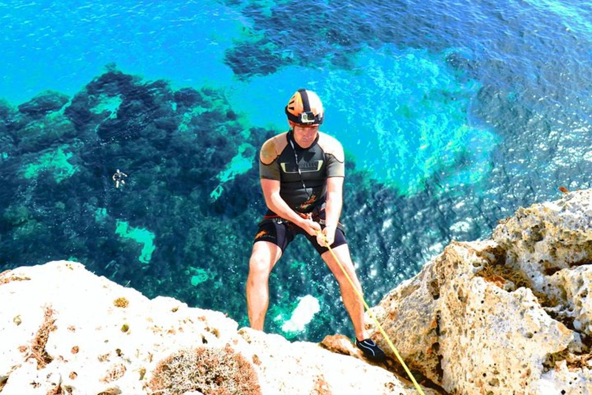 muž stojící na vrcholu skály před oceánem