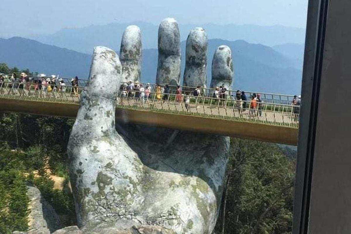 un gruppo di persone che attraversa un ponte con una mano gigante