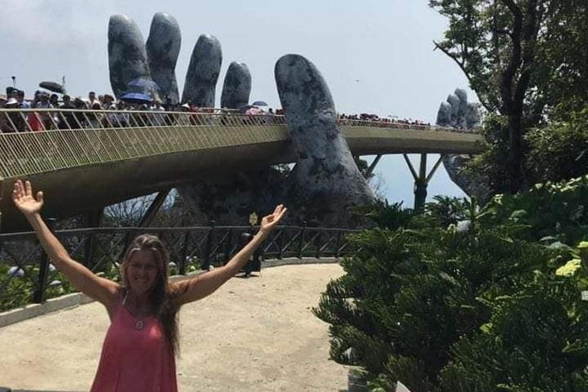 una donna in piedi davanti a un ponte con le mani alzate