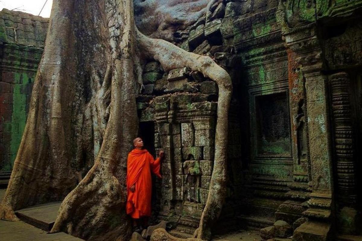 un uomo in una tunica arancione in piedi accanto a un albero