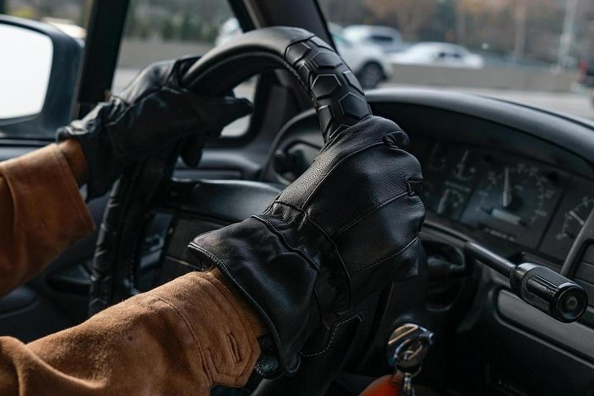 a person wearing a black gloves driving a car