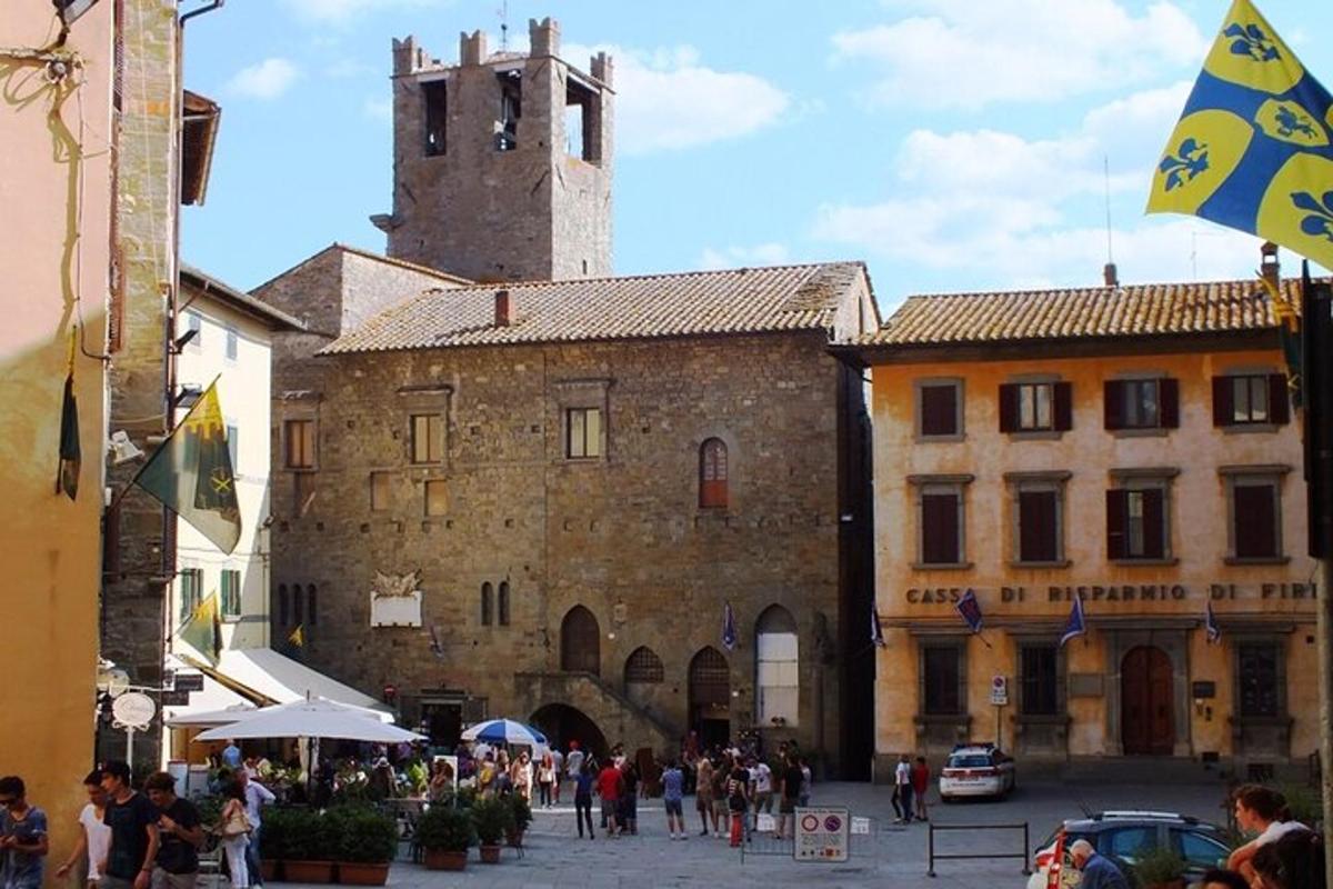 un gruppo di persone che camminano intorno a un edificio con una torre