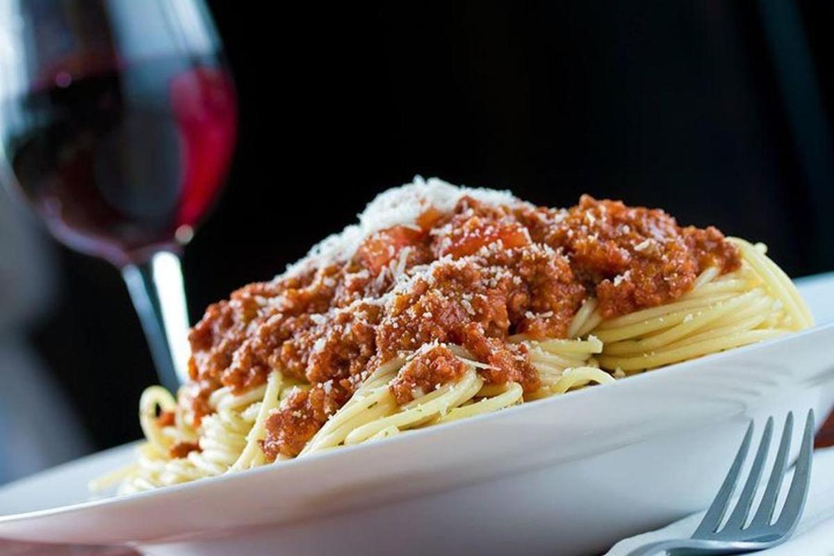 un piatto di pasta al ragù e un bicchiere di vino