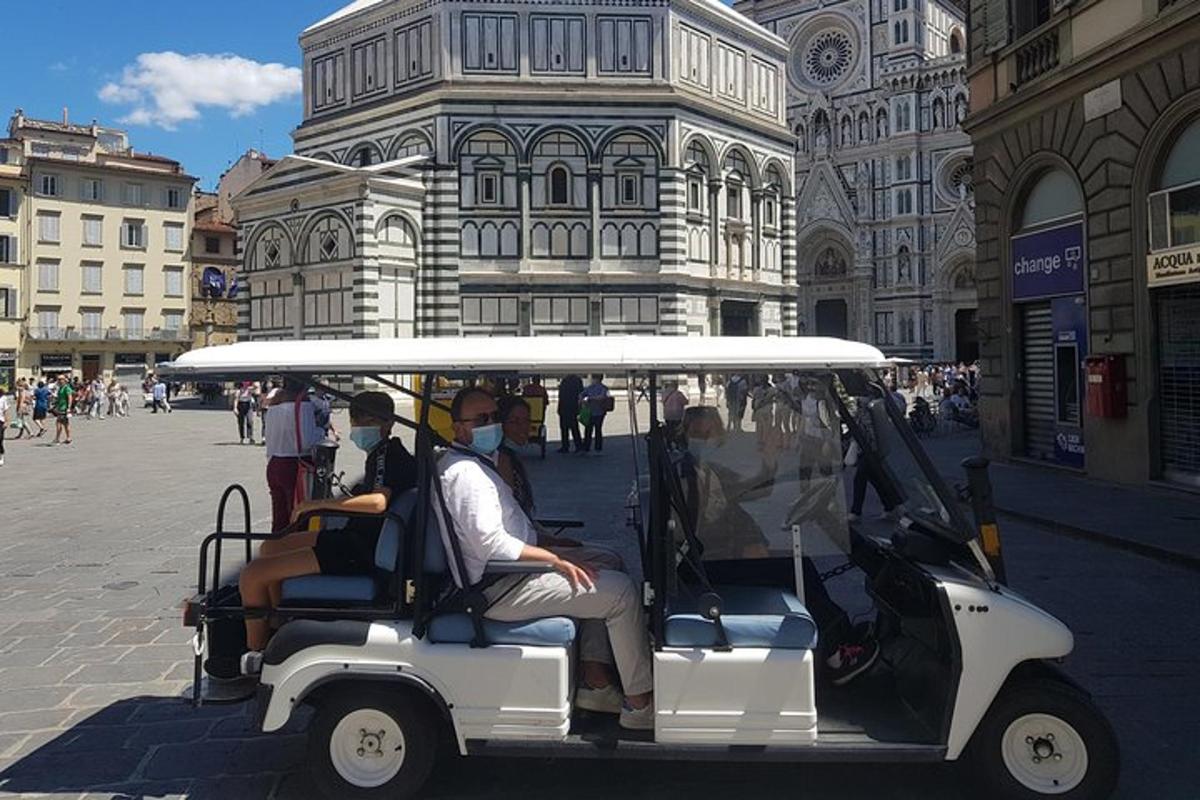 skupina lidí jedoucích v golfovém vozíku