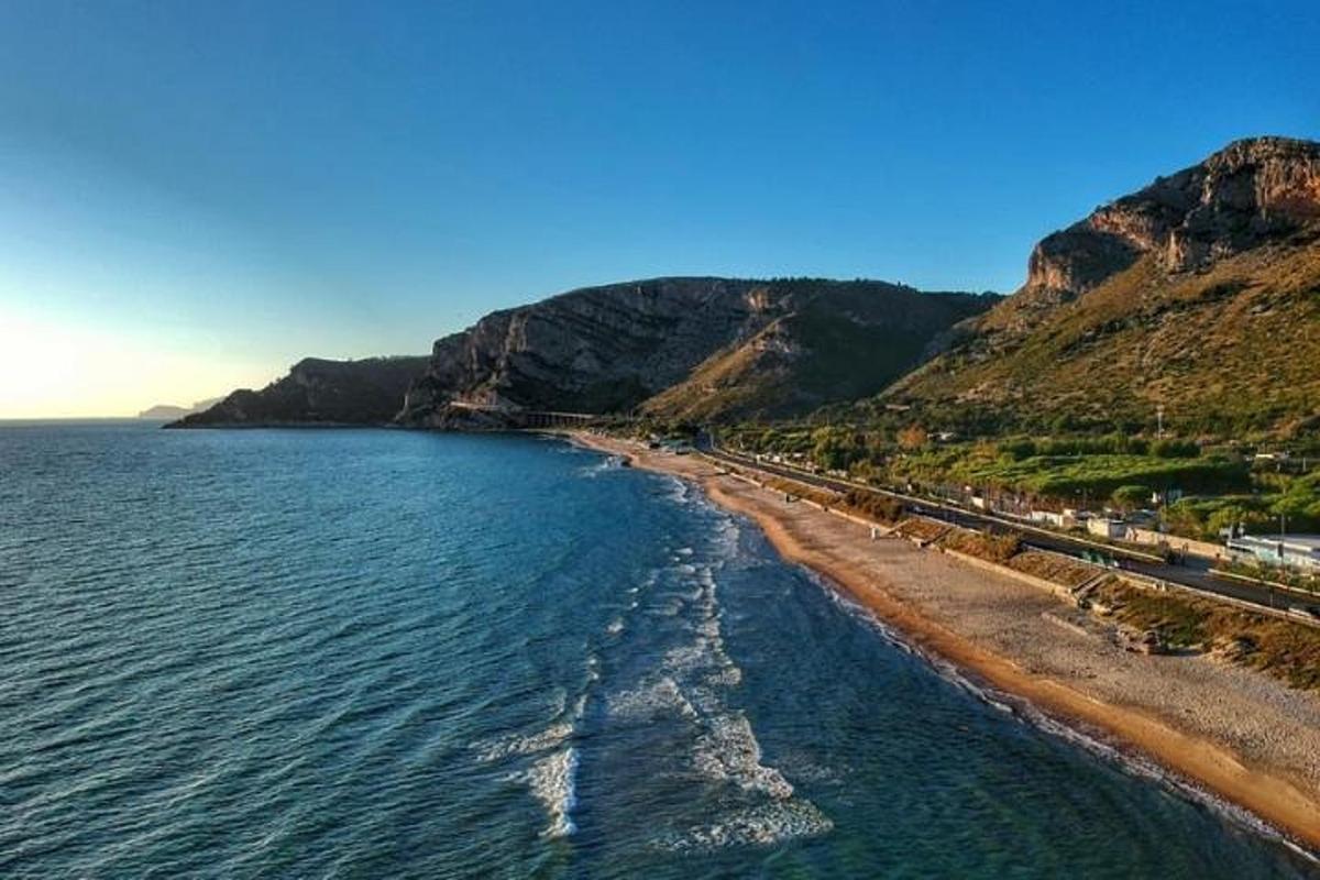 an aerial view of a beach with a mountain