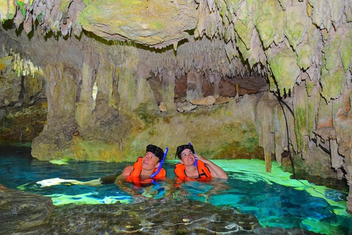 Dos personas nadando en una piscina de agua en una cueva.