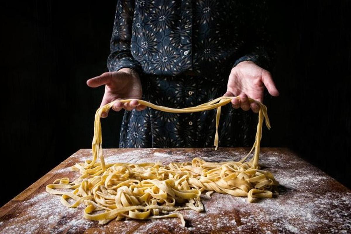 seseorang yang memegang sekumpulan pasta di atas papan pemotong