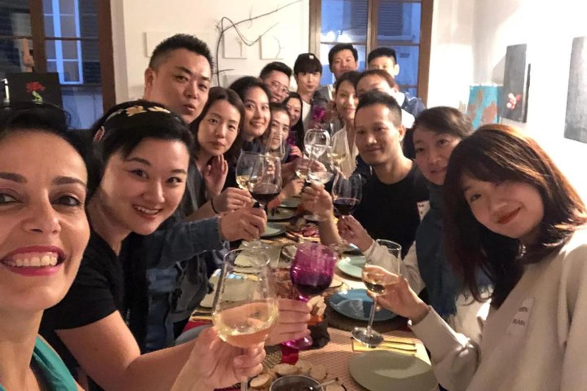 um grupo de pessoas sentadas ao redor de uma mesa segurando taças de vinho