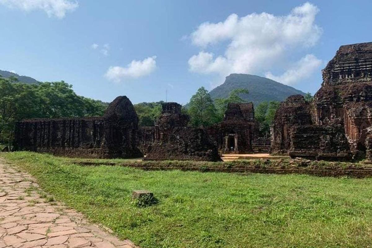 một cánh đồng trước một tòa nhà với những ngọn núi ở phía sau